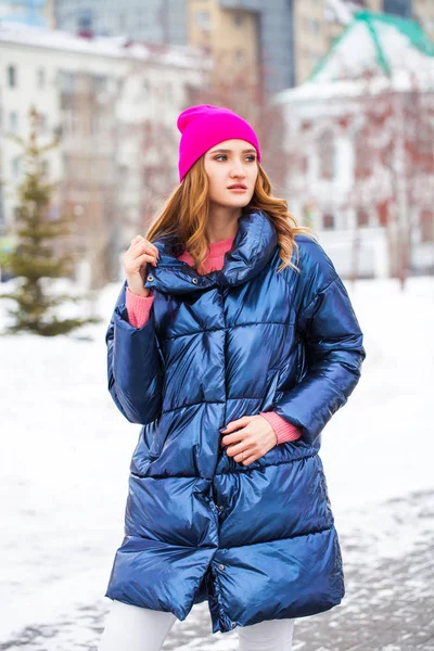 Young blonde woman in blue down jacket in winter street — Stock Photo, Image