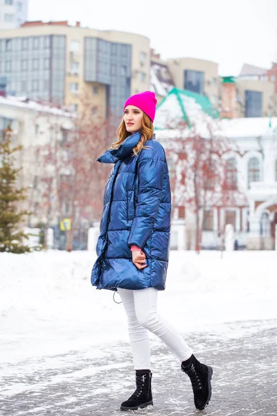 Young blonde woman in blue down jacket in winter street — 스톡 사진