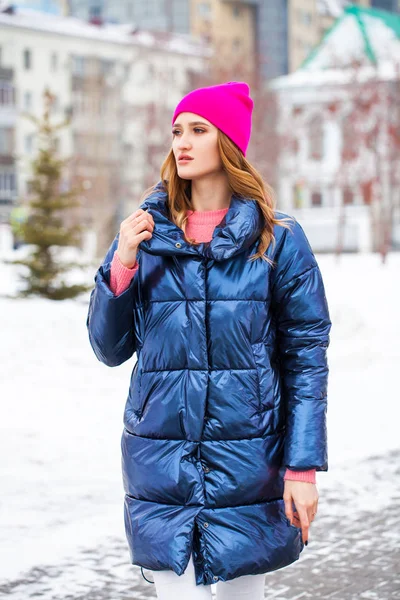 Young blonde woman in blue down jacket in winter street — 스톡 사진