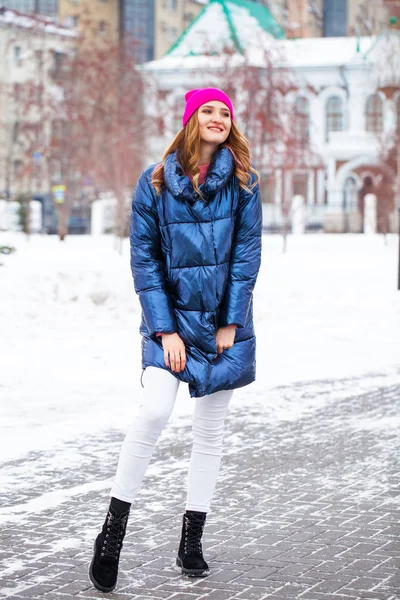 Young blonde woman in blue down jacket in winter street — Stock Photo, Image