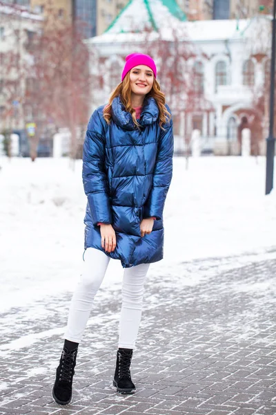 Ung blond kvinna i blå dunjacka på vintern gata — Stockfoto