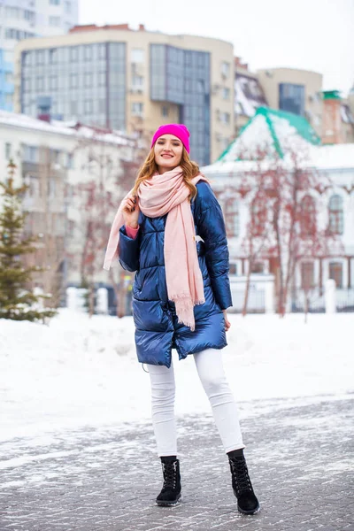 Jonge blonde vrouw in blauw donsjas in de winter straat — Stockfoto