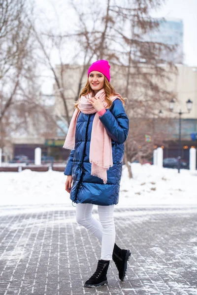 Young blonde woman in blue down jacket in winter street — 스톡 사진