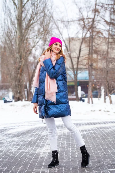 Jonge blonde vrouw in blauw donsjas in de winter straat — Stockfoto