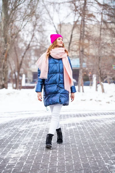 Young blonde woman in blue down jacket in winter street — Stock Photo, Image