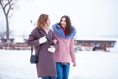 İki mutlu güzel kız arkadaş kışın şehir merkezinde yürür.