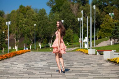 Yaz sokakta yürüyen pembe elbiseli genç güzel kadın