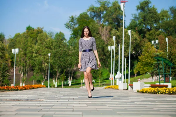 Young beautiful woman in gray dress walking on the summer street — Stock Photo, Image