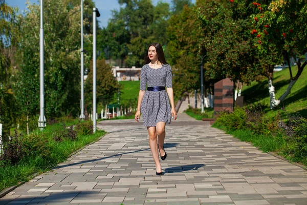 Young beautiful woman in gray dress walking on the summer street — Stock Photo, Image