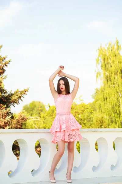Jonge mooie vrouw in roze jurk wandelen op de zomer straat — Stockfoto