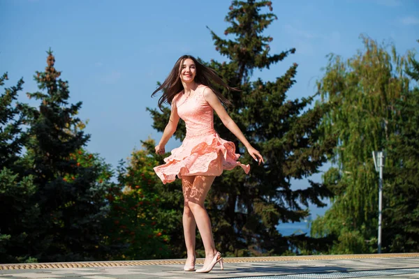 stock image Young beautiful woman in pink dress walking on the summer street