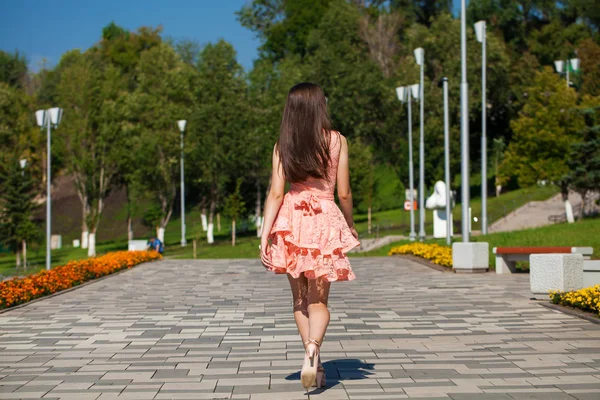 年轻的美丽的女人在粉红色的礼服走在夏天的大街上 — 图库照片