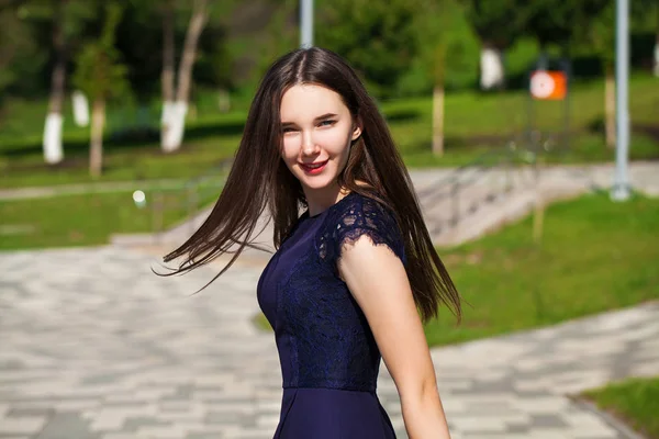 Jonge mooie vrouw in donker blauwe jurk wandelen op de zomer s — Stockfoto