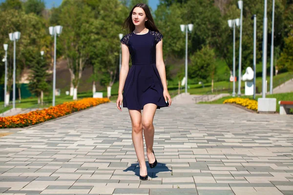 Jonge mooie vrouw in donker blauwe jurk wandelen op de zomer s — Stockfoto