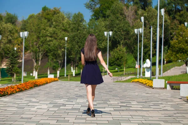 Молодая красивая женщина в синем платье ходит по летней улице — стоковое фото