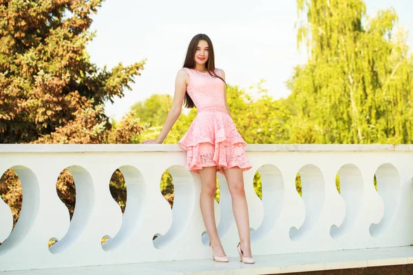 Молода красива жінка в рожевій сукні, що йде на літній вулиці — стокове фото