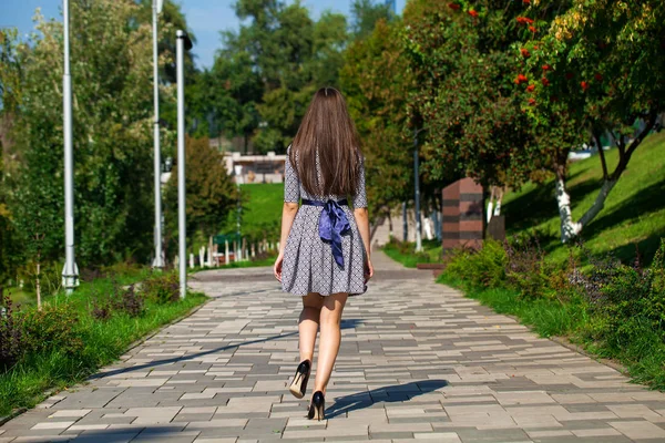 Young beautiful woman in gray dress walking on the summer street — Stock Photo, Image