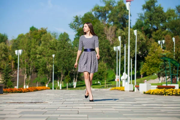 Young beautiful woman in gray dress walking on the summer street — Stock Photo, Image