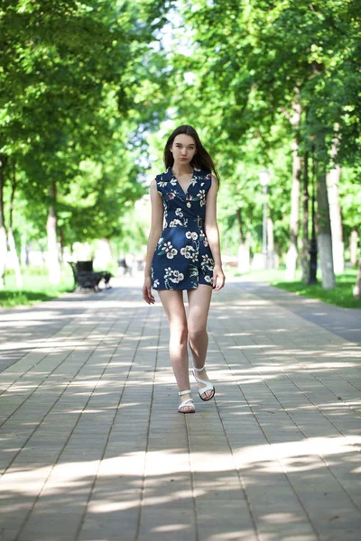 Jovem mulher bonita em um vestido curto azul andando na estrada — Fotografia de Stock