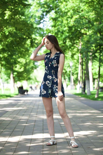 Young beautiful woman in a blue short dress walking on the road — Stock Photo, Image