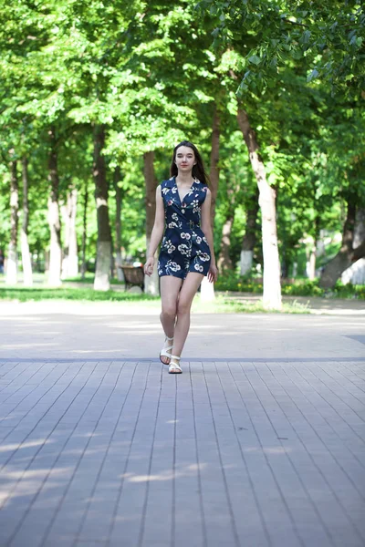 Jovem mulher bonita em um vestido curto azul andando na estrada — Fotografia de Stock