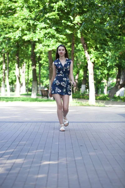 道路の上を歩く青いショート ドレスの若い美しい女性 — ストック写真