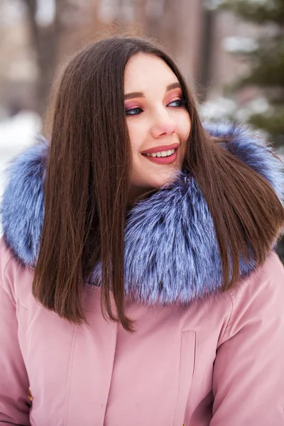 Young blonde woman in blue down jacket in winter street — 스톡 사진