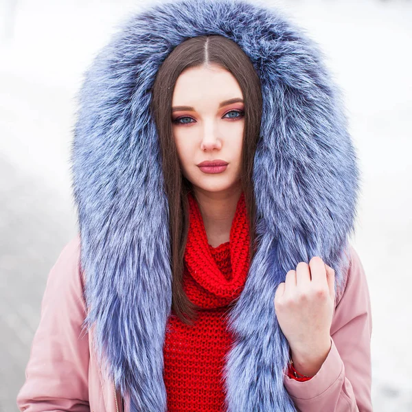 Jonge blonde vrouw in blauw donsjas in de winter straat — Stockfoto