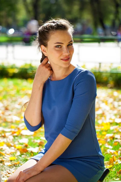 Νέα όμορφη μελαχρινή γυναίκα με μπλε φόρεμα στο φθινόπωρο πάρκο — Φωτογραφία Αρχείου
