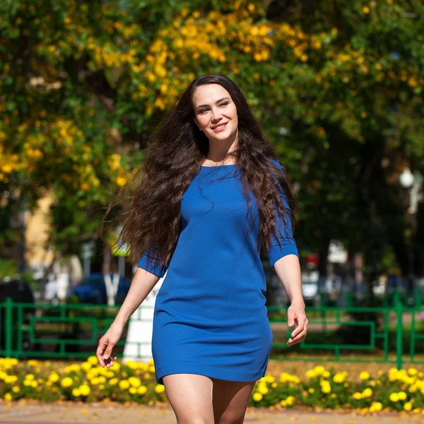 Krásná brunetka v modrých šatech, které chodí po ulici, — Stock fotografie