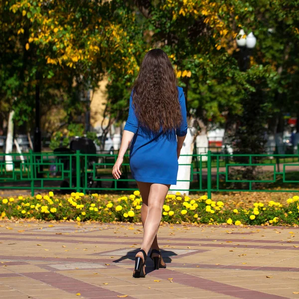 Mooie brunette vrouw in een blauwe jurk wandelen op straat, — Stockfoto