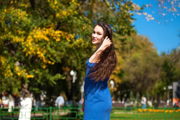 Mooie brunette vrouw in een blauwe jurk wandelen op straat, — Stockfoto