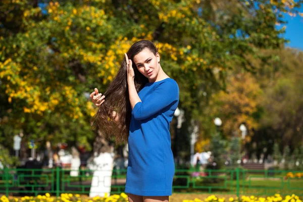 Krásná brunetka v modrých šatech, které chodí po ulici, — Stock fotografie