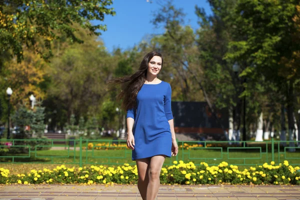 Krásná brunetka v modrých šatech, které chodí po ulici, — Stock fotografie