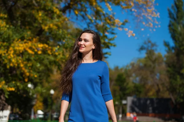 Mooie brunette vrouw in een blauwe jurk wandelen op straat, — Stockfoto