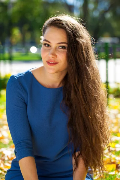 Joven hermosa mujer morena en vestido azul en el parque de otoño — Foto de Stock