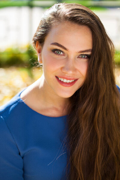 Молодая красивая брюнетка в синем платье в осеннем парке
