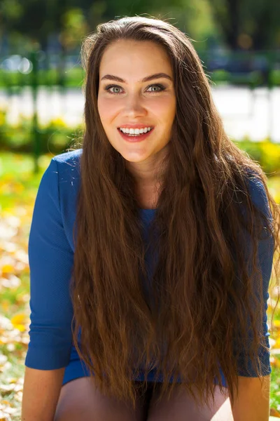 Young beautiful brunette woman in blue dress in autumn park — Stock Photo, Image