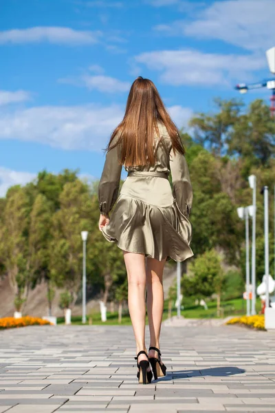 年轻的美丽的女人在绿色的礼服走在夏天的树 — 图库照片