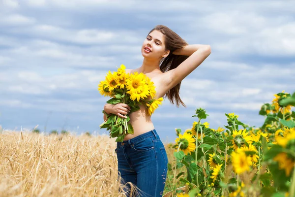 Menina sexy com um buquê de girassóis posando em um backgro campo — Fotografia de Stock