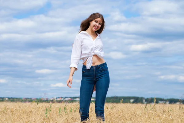 Junge brünette Frau in weißem Hemd und blauer Jeanshose — Stockfoto