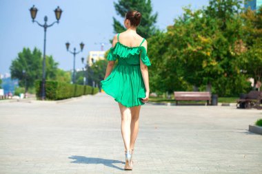 Yeşil elbise genç güzel esmer kız EMB boyunca yürür