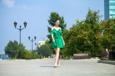 Yeşil elbise genç güzel esmer kız EMB boyunca yürür