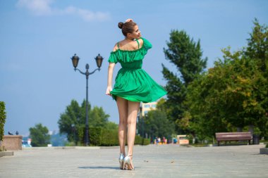 Yeşil elbise genç güzel esmer kız EMB boyunca yürür