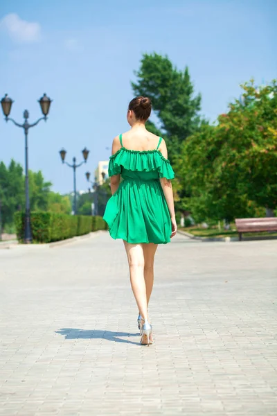 Fiatal, gyönyörű barna lány zöld ruhában sétál az emb — Stock Fotó