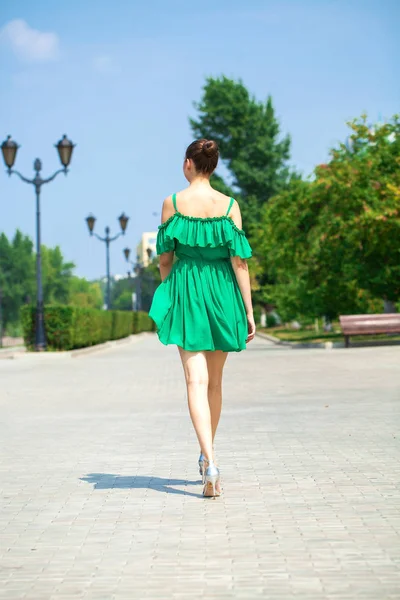 Jonge mooie brunette meisje in groene jurk wandelingen langs de EMB — Stockfoto