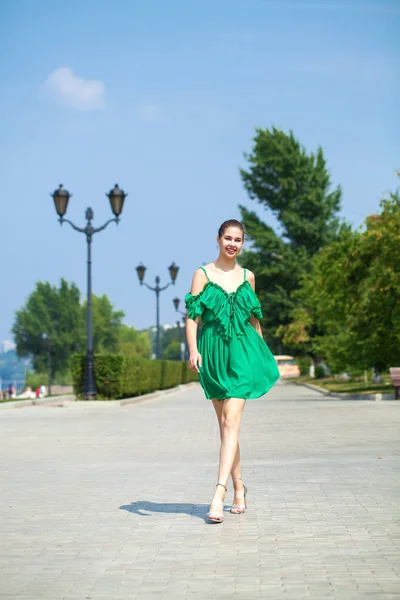 Young beautiful brunette girl in green dress walks along the emb — Stock Photo, Image