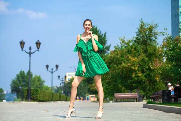 年轻的美丽的女人在绿色的礼服走在夏天的树 — 图库照片