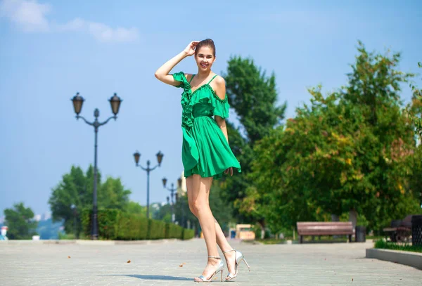 Молодая красивая женщина в зеленом платье ходить по летней улице — стоковое фото