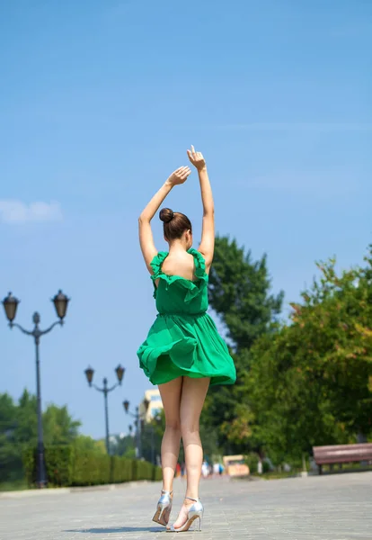 緑のドレスを着た若い美しいブルネットの女の子は、embに沿って歩きます — ストック写真